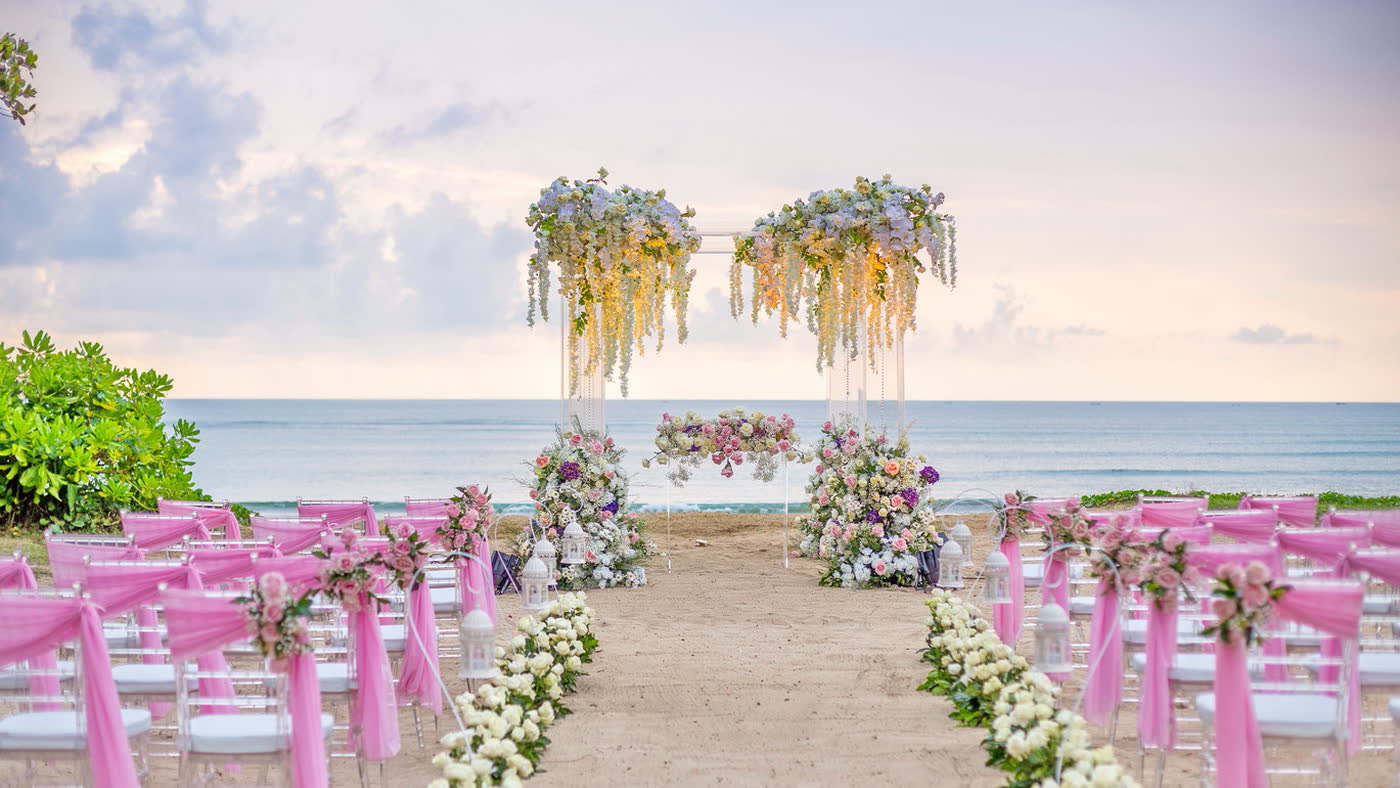 Beach ceremony aisle framed by pastel flowers by CITTA